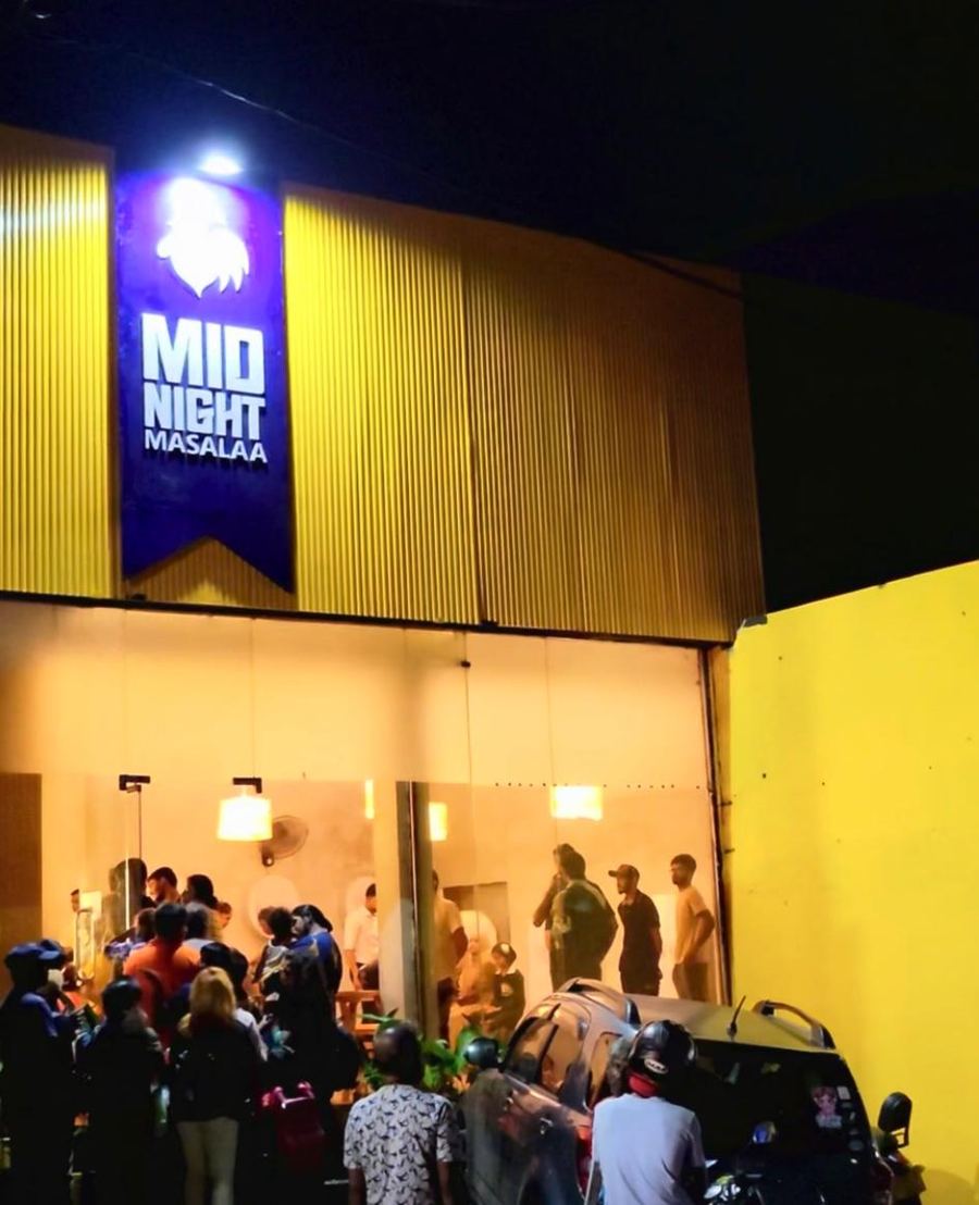 Night crowd outside Midnight Masalaa with the sign glowing